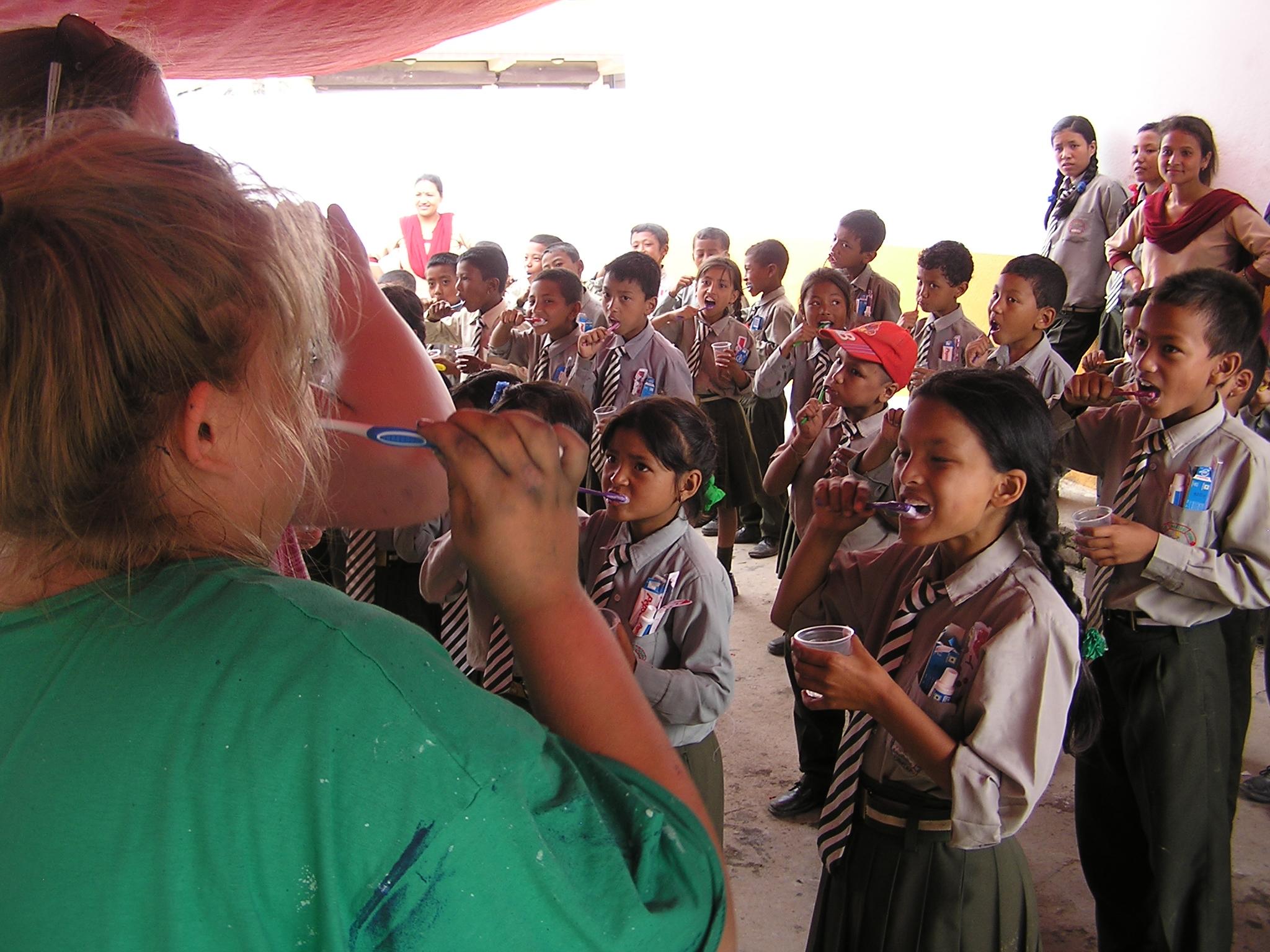 Durante sus prácticas para estudiantes de Odontología, una interna enseña sobre higiene dental en una escuela de Nepal. Interna de Odontología enseñando a unos niños a cepillarse correctamente los dientes.